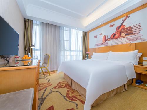 a hotel room with a large bed and a flat screen tv at Vienna Hotel Hubei Xiangyang Tanxi Road in Xiangyang