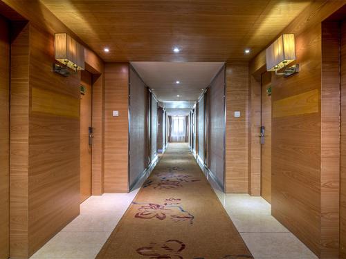 広州市にあるヴィエナ ホテル 広州エアポートの木の壁の廊下、カーペットの長い廊下