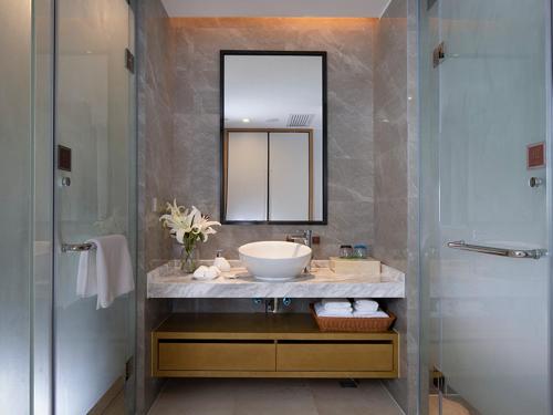 a bathroom with a sink and a mirror and a shower at Vienna Hotel(Haikou International Convention and Exhibition Center) in Haikou
