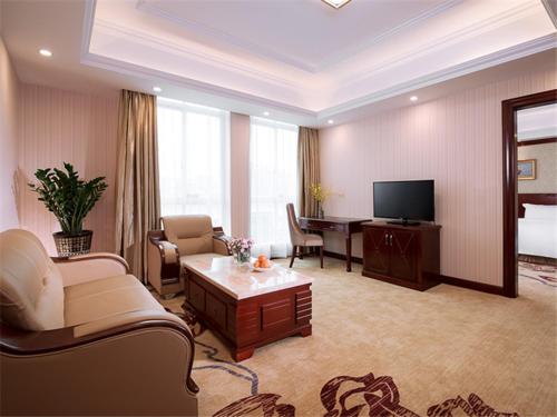 uma sala de estar com um sofá, uma mesa e uma televisão em Vienna Hotel Guangzhou Dongpu Bus Station em Guangzhou
