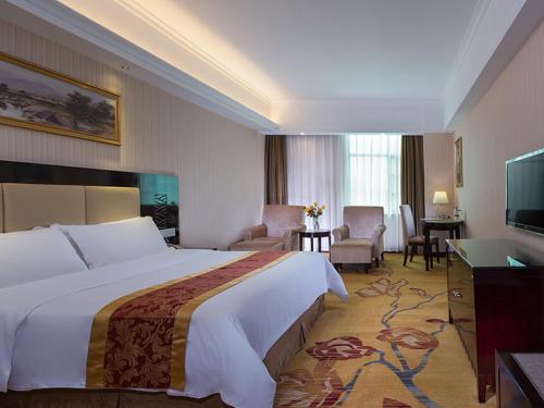 a hotel room with a large bed and a living room at Vienna Hotel Baoan Liutang in Xin'an