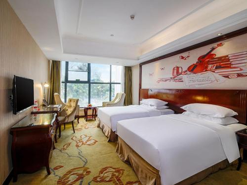 a hotel room with two beds and a desk at Vienna Hotel Shenzhen Shuiku New Village in Shenzhen