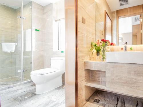 a bathroom with a toilet and a sink and a shower at Vienna International Hotel Huhan Jiedaokou in Wuhan