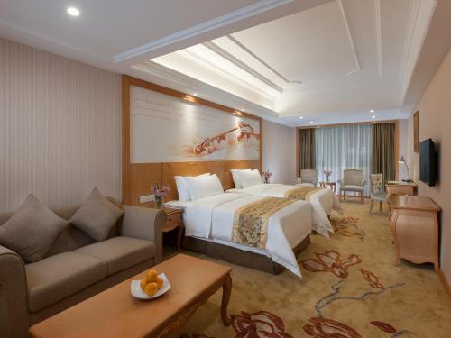 Cette chambre comprend un grand lit et un canapé. dans l'établissement Vienna International Hotel Guangzhou Airport Xinshi, à Canton