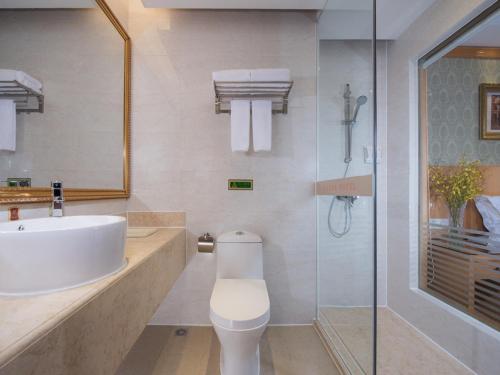 uma casa de banho com um lavatório, um WC e um chuveiro em Vienna Hotel Shenzhen Buji Ganli Road em Longgang