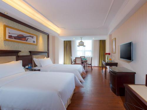 a hotel room with two beds and a television at Vienna Hotel Guangzhou Shiling in Huadu