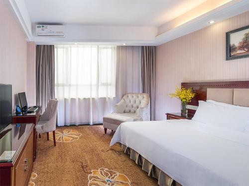 a hotel room with a large bed and a chair at Vienna Hotel Longgang Nanlian in Longgang