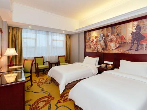 une chambre d'hôtel avec 2 lits et un tableau mural dans l'établissement Vienna Hotel Huizhou Huiyang Danshui Road, à Huizhou