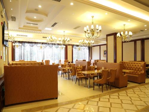 a restaurant with tables and chairs and chandeliers at Vienna International Hotel Changsha Yinshan Road in Changsha