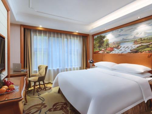 um quarto de hotel com uma grande cama branca e uma janela em Vienna International Hotel Nanjing South Railway Station em Nanquim