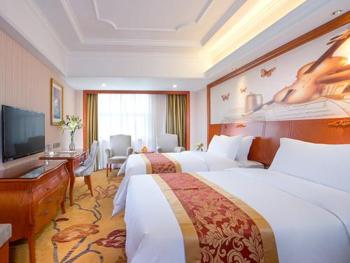 a hotel room with two beds and a flat screen tv at Vienna Hotel Shenzhen Bantian South Huancheng Road in Shenzhen
