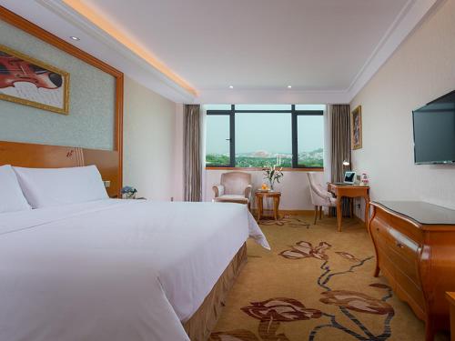 a hotel room with a large bed and a desk at Vienna Hotel (Quanzhou West Lake Store) in Quanzhou