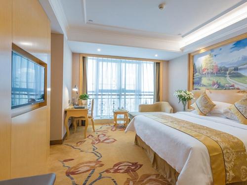 ein Hotelzimmer mit einem großen Bett und einem großen Fenster in der Unterkunft Vienna Hotel Guangxi Nanjing Nanhu Park in Nanning