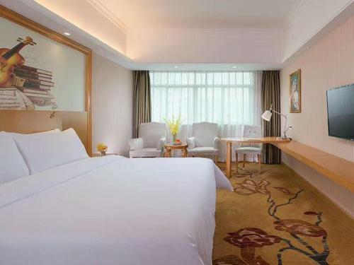 ein Hotelzimmer mit einem großen Bett und einem Schreibtisch in der Unterkunft Vienna Hotel (Huizhou Daya Bay Xinyi Store) in Huizhou