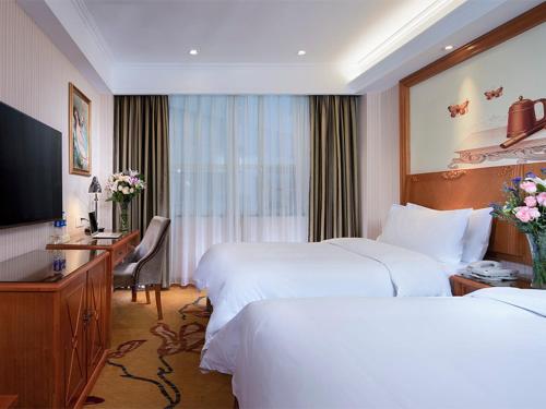 a hotel room with two beds and a desk at Vienna Classic Hotel (Anlu Hengkun) in Zhulin