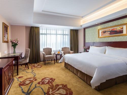 a hotel room with a large bed and a desk at Vienna Hotel Guangzhou Jinshazhou in Nanhai