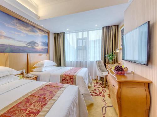 ein Hotelzimmer mit zwei Betten und einem Flachbildfernseher in der Unterkunft Vienna Hotel Guilin AIrport Road Rongshan in Guilin