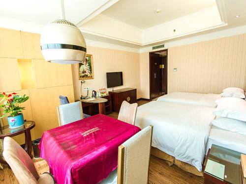a bedroom with a large bed with a pink blanket on it at Vienna International Hotel Zhangjiajie Tianmen Mountain in Zhangjiajie
