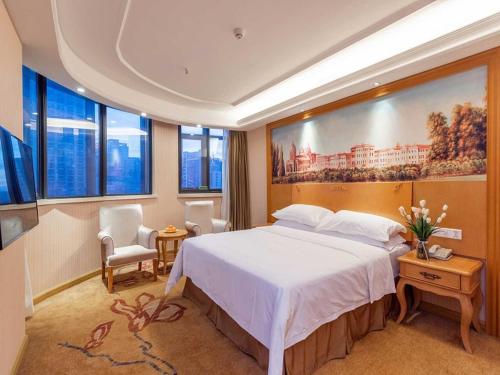 a bedroom with a large bed with a painting on the wall at Vienna International Hotel Zhuzhou Railway Station Central Plaza in Zhuzhou
