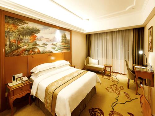 a hotel room with a large bed and a desk at Vienna Hotel Shaoguan Wuli Pavilion in Shaoguan