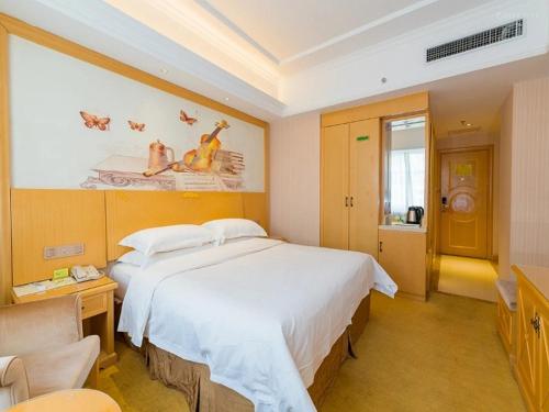 a bedroom with a large white bed and a desk at Vienna Hotel Xining Shengli Road in Xining