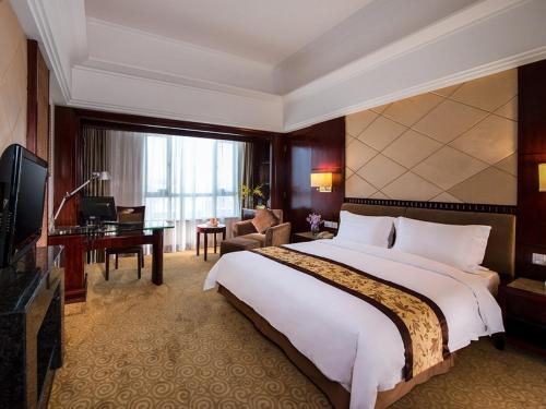 een hotelkamer met een groot bed en een bureau bij Vienna International Hotel Dongguan Changping Swan Lake Road in Dongguan