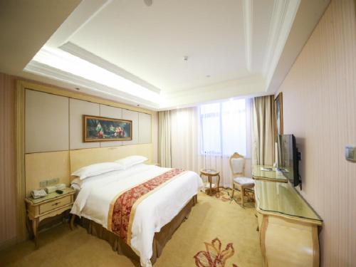 Vienna Hotel Shanghai Hongqiao Convention & Exhibition Center في شانغهاي: غرفه فندقيه سرير كبير وتلفزيون