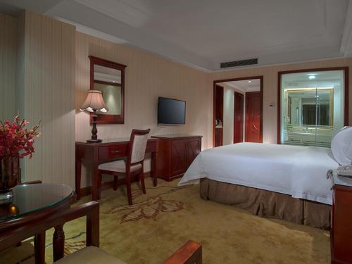 een hotelkamer met een groot bed en een bureau bij Vienna Hotel Shenzhen Futian Bagua Road in Shenzhen
