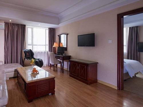 a hotel room with a bed and a living room at Vienna Hotel Dongguan Chang'an Mid Zhen'an Road in Dongguan