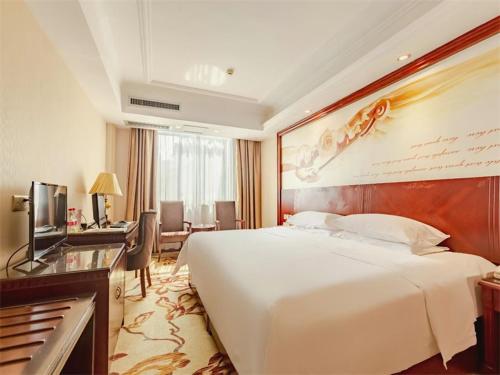 a hotel room with a large bed and a desk at Vienna Hotel Guilin Railway Staion in Guilin