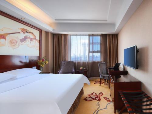 Pokój hotelowy z dużym łóżkiem i telewizorem w obiekcie Vienna Hotel Nanchang Ruzi Road w mieście Nanchang
