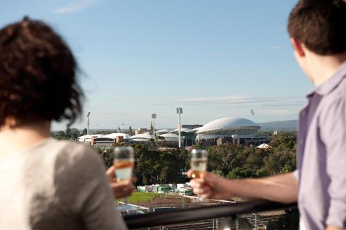 two people standing on a balcony with their cell phones at Adelaide Riviera Hotel in Adelaide