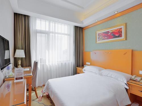 a hotel room with a bed and a desk and a bed sidx sidx at Vienna Hotel Tianjin Huanghe Road in Tianjin
