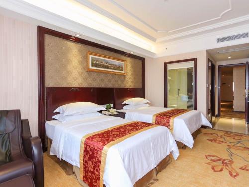 a hotel room with two beds and a couch at Vienna International Hotel Shanghai Pudong Xinchang Old Town Subway Station in Nanhui