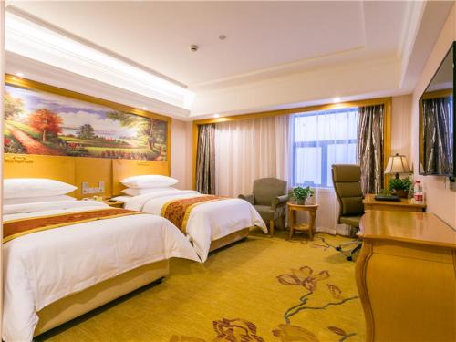 a hotel room with two beds and a desk at Vienna International Hotel Shanghai Pudong New International Exbition Central in Shanghai