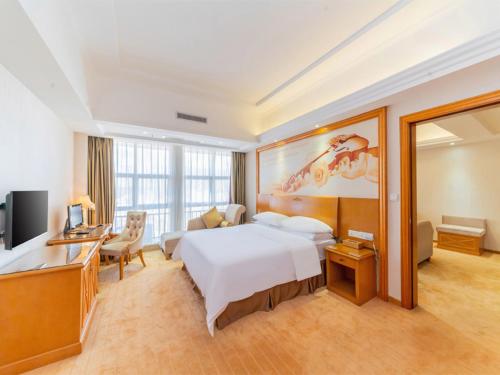 Habitación grande con cama y escritorio. en Vienna Hotel Shiyan Guangming Road, en Bao'an