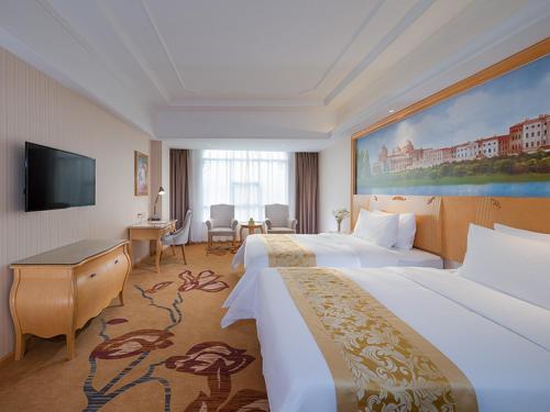 a hotel room with two beds and a flat screen tv at vienna Hotel (fujian quanzhou dehua station) in Dehua