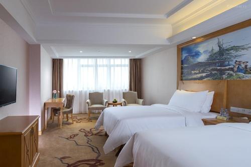 a hotel room with two beds and a flat screen tv at Vienna International Hotel Guangdong Foshan Nanhai Heshun in Nanhai