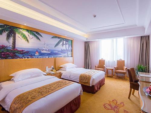 a hotel room with two beds and a large painting at Vienna International Hotel Shanghai Jinqiao Industrial Park North Yanggao Road in Shanghai