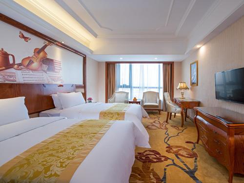 Vienna International Hotel Jieyang Yangmei Yudu في Jieyang: غرفة فندقية بسريرين وتلفزيون بشاشة مسطحة