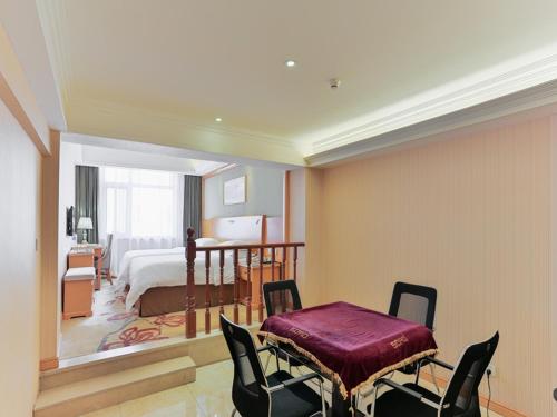 a bedroom with a bed and a table and chairs at Vienna Hotel Tianjin Huanghe Road in Tianjin