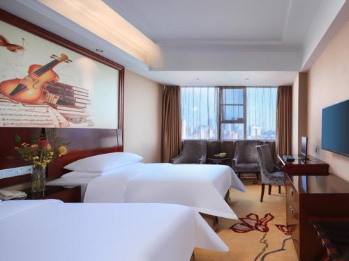 a hotel room with two beds and a living room at Vienna Hotel Nanchang Ruzi Road in Nanchang