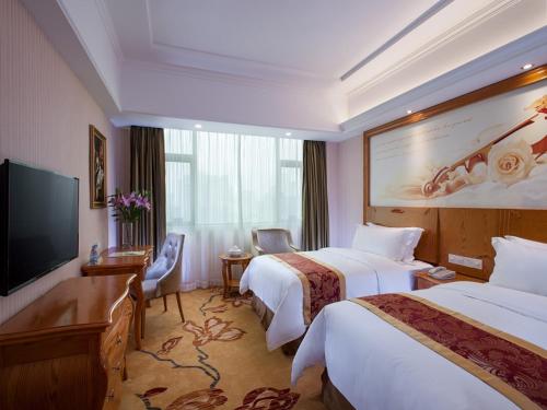 a hotel room with two beds and a flat screen tv at Vienna Hotel Jieyang Danpu Road in Jieyang