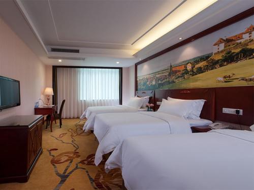 a hotel room with four beds and a painting on the wall at Vienna 3 Best Hotel Guangzhou Zengcheng Xintang Harbour Avenue in Zengcheng