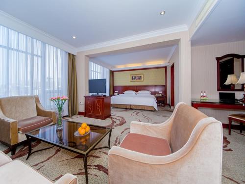 Habitación de hotel con cama y sala de estar. en Vienna International Hotel Xiangyang Railway Station, en Xiangyang