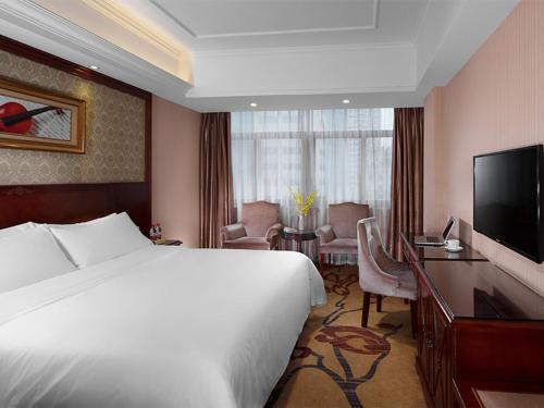 長沙市にあるVienna Hotel Changsha Mid Furong Roadのベッド、デスク、テレビが備わるホテルルームです。