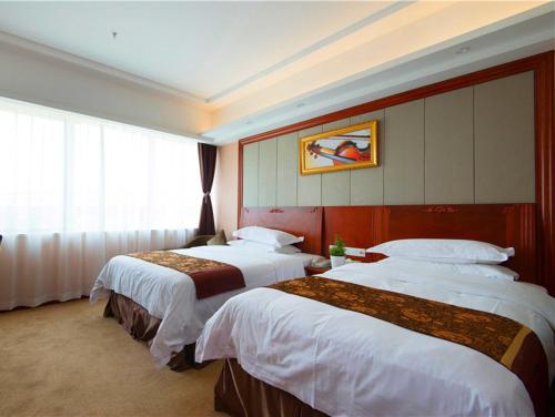 上海市にあるウィーン ホテル 上海 浦東空港 華夏路のベッド3台と窓が備わるホテルルームです。