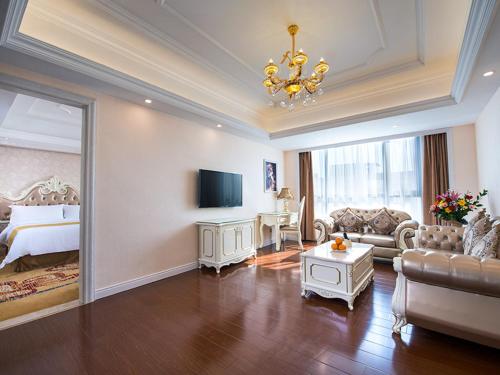 Vienna International Hotel Jieyang Yangmei Yudu في Jieyang: غرفة كبيرة بها سرير وغرفة معيشة