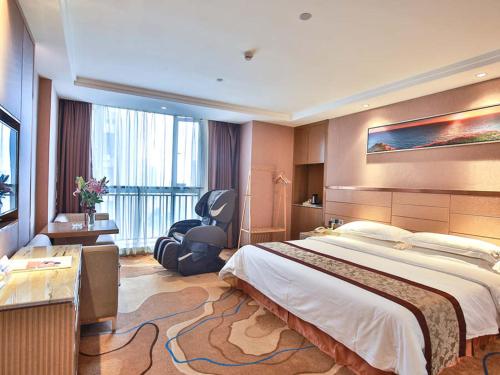 武漢市にあるVienna International Hotel Huhan Jiedaokouの大きなベッドと椅子が備わるホテルルームです。