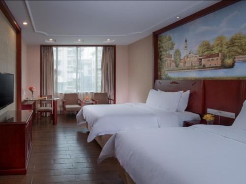 um quarto de hotel com duas camas e uma mesa em Vienna hotel (sanshui wanda store) em Foshan